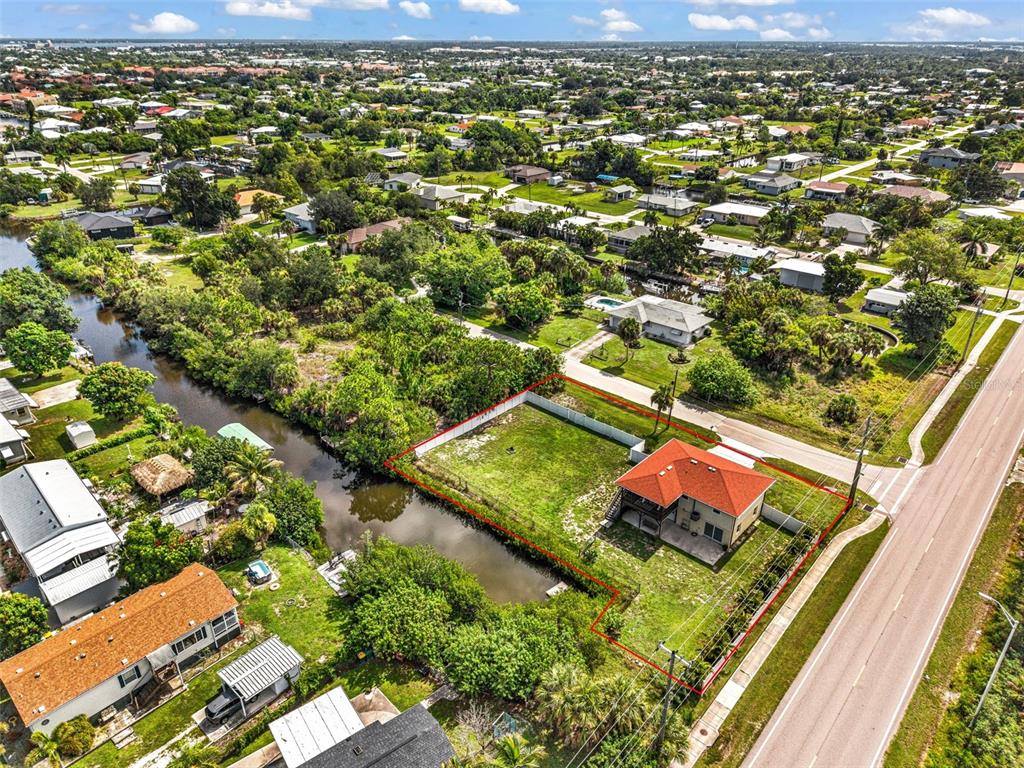 An aerial view shows a house with a red roof situated on a corner lot — 3129 BANYAN WAY, PUNTA GORDA, FL