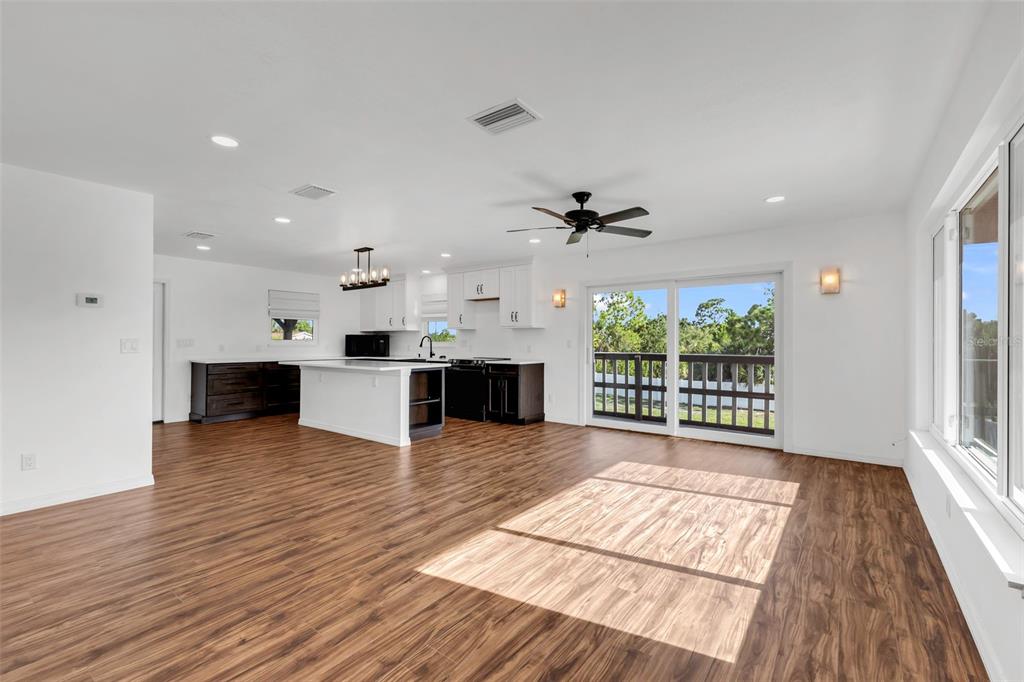 An open-concept kitchen and living area features white cabinetry, a kitchen island, and wood-look flooring — 3129 BANYAN WAY, PUNTA GORDA, FL