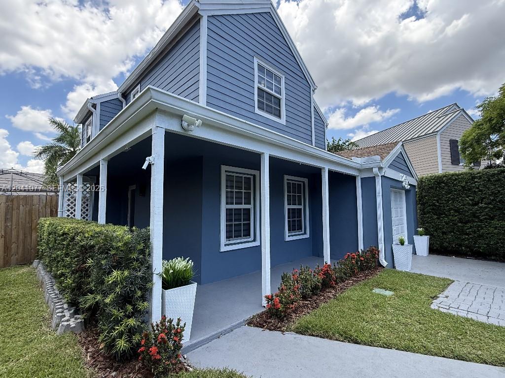 A blue two-story house features a covered front porch, white trim, and landscaped hedges — 11745 SW 116th Ter, Miami FL 33186, MIAMI, FL