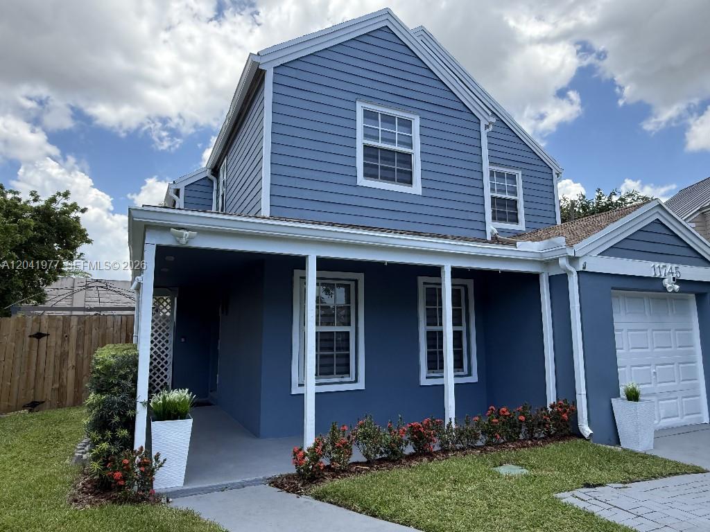 A two-story blue house features a covered front porch, white trim, and a garage — 11745 SW 116th Ter, Miami FL 33186, MIAMI, FL