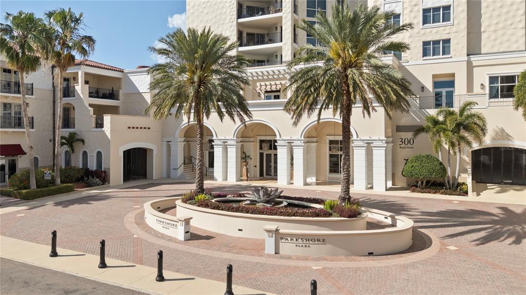 The exterior of a multi-story building features a circular driveway with a central fountain — 300 BEACH DRIVE NE UNIT 302, ST PETERSBURG, FL