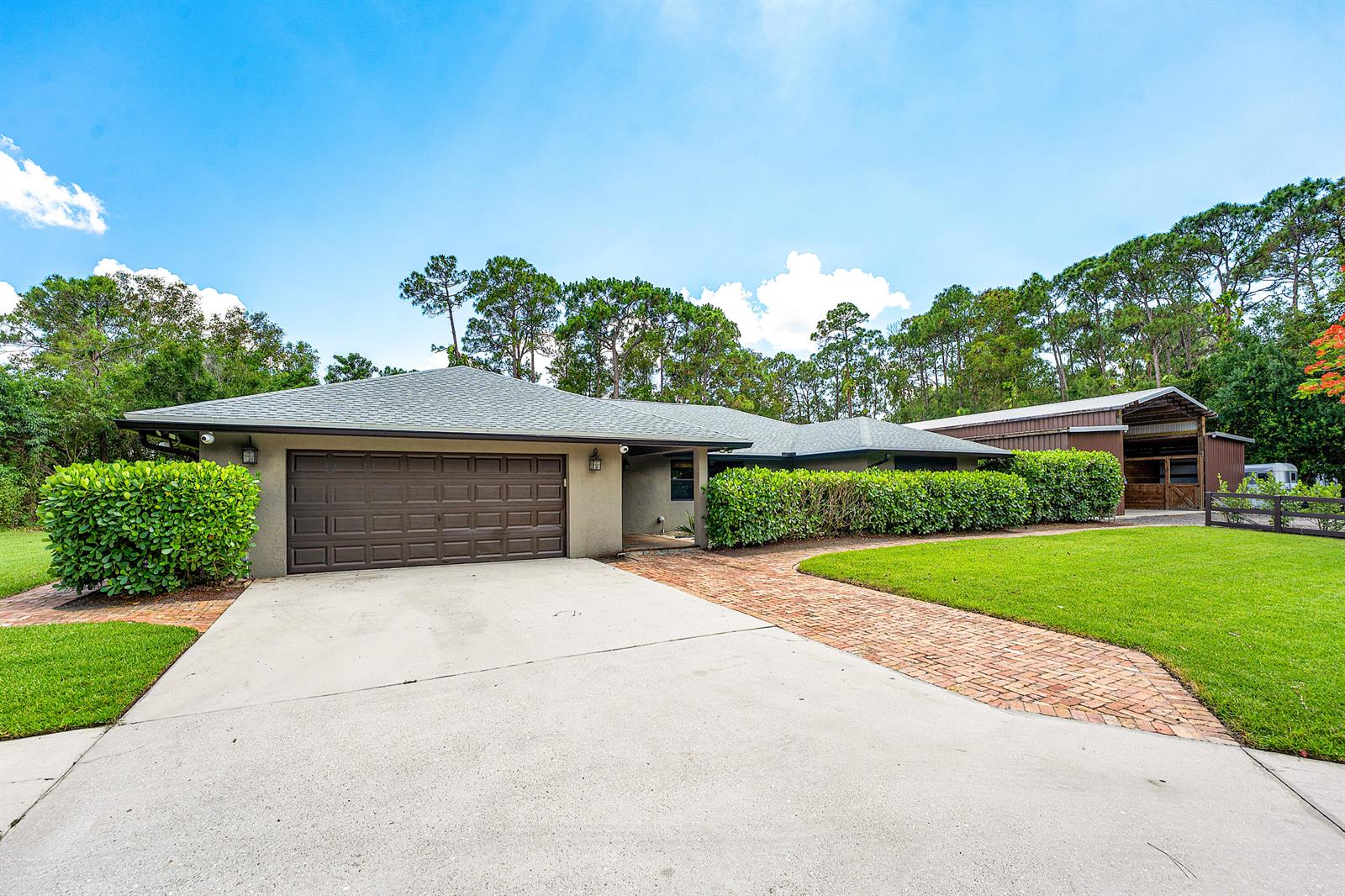 A single-story house with a brown garage, brick walkway, and a detached barn structure — 13530 N 59th Ct Court N, FL 33411, FL