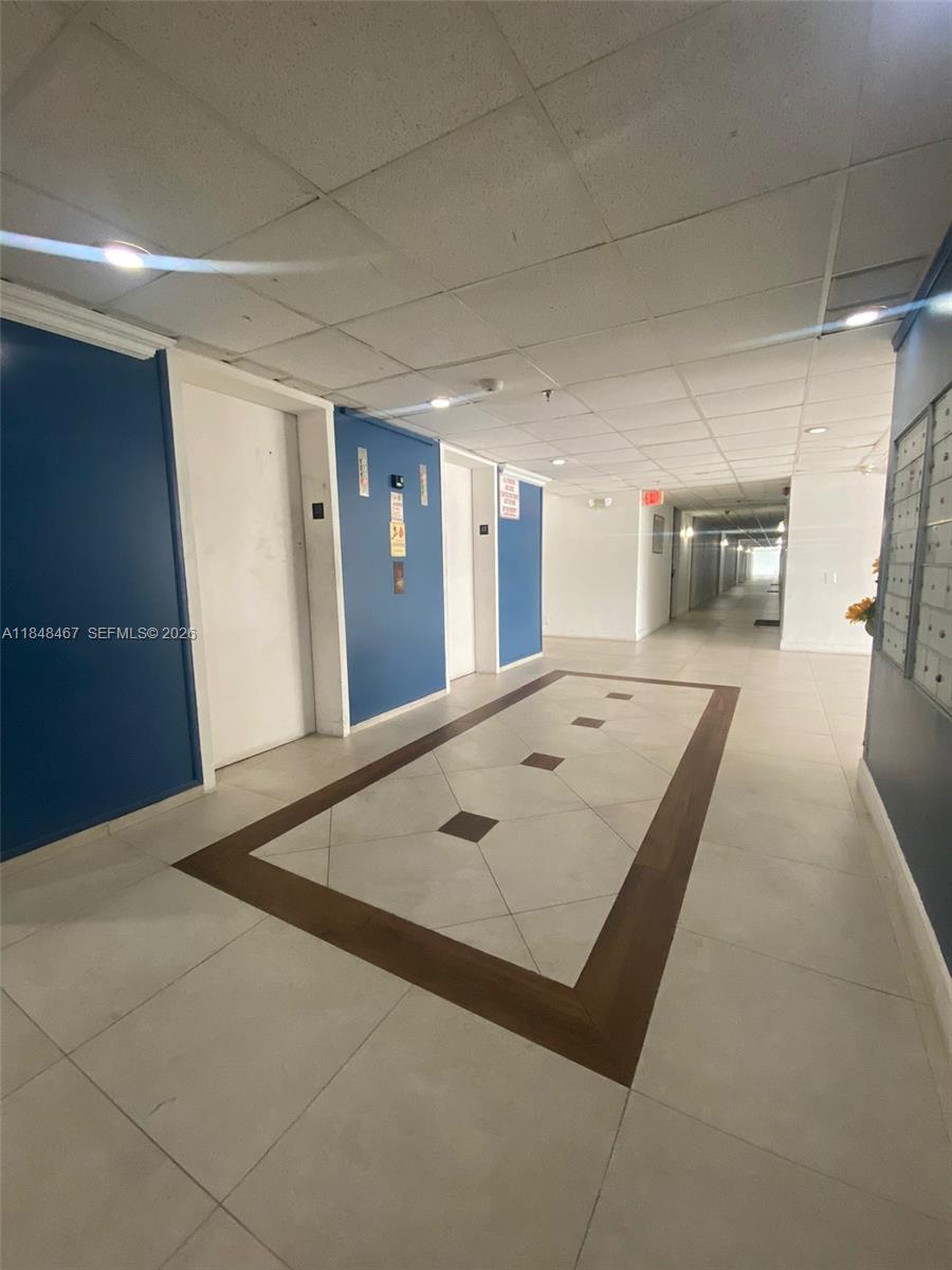 A hallway features blue accent walls, two elevator doors, and a tiled floor with a border — 16450 NW 2nd Ave # 404, Miami FL 33169, MIAMI, FL