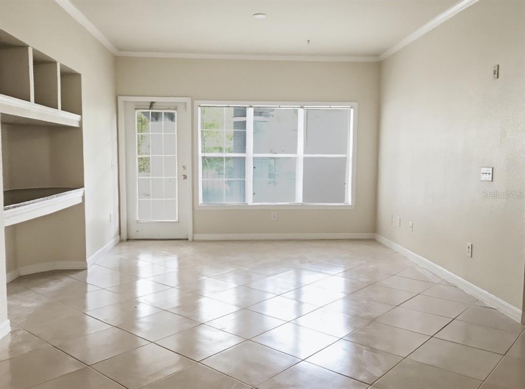 An empty room with beige tile flooring, a glass-paned door, and built-in shelving — 3735 CONROY ROAD UNIT 2211, ORLANDO, FL