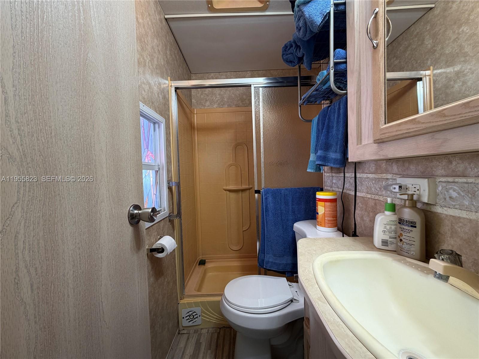 A small bathroom features a tan shower stall, a white toilet, and a vanity sink — 1361 Overseas Hwy G13, Marathon FL 33050, MARATHON, FL
