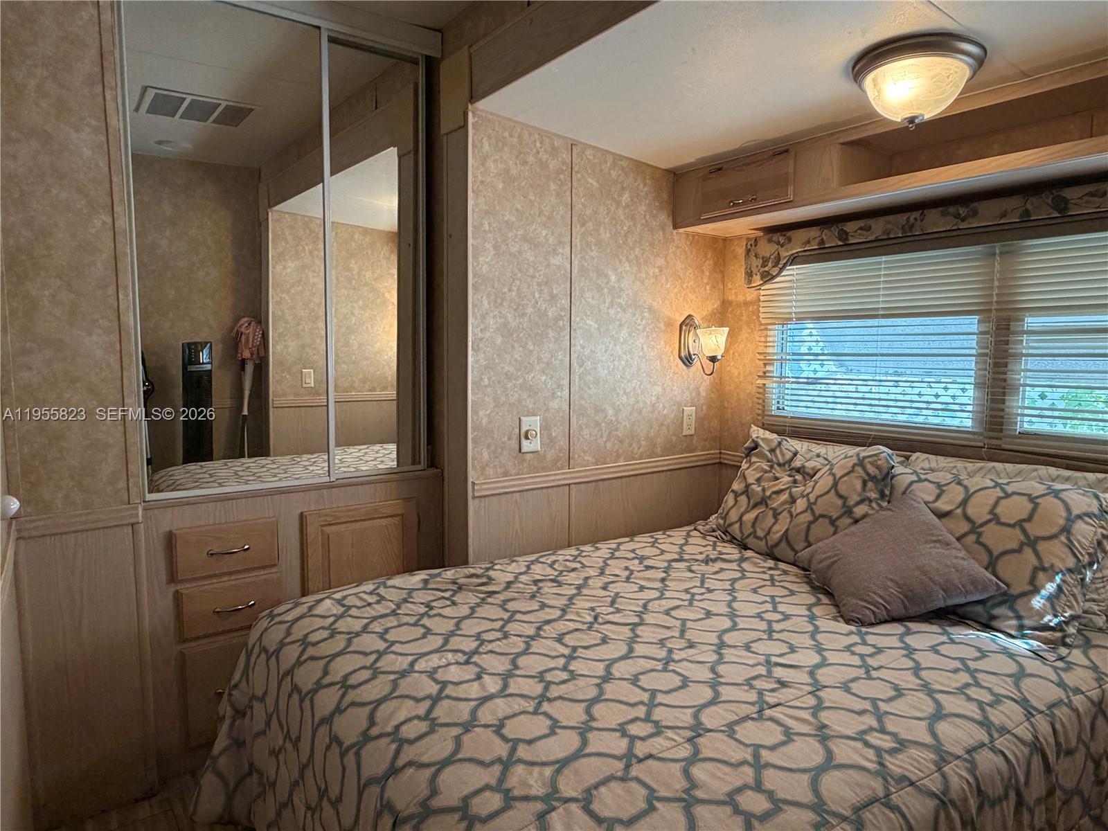 A bedroom features a bed with patterned bedding, wood-paneled walls, and a mirrored closet — 1361 Overseas Hwy G13, Marathon FL 33050, MARATHON, FL