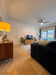 A living room features a blue sofa, a television on a wooden console, and a ceiling fan — 2200 TUSCANY TRACE UNIT 1714, PALM HARBOR, FL