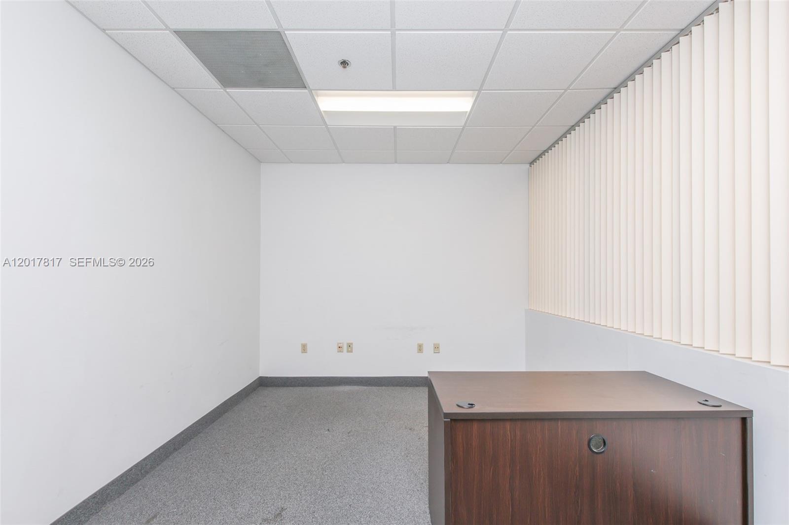 An empty office space features white walls, gray carpeting, a drop ceiling, and vertical blinds — 1900 Glades Rd # 280, Boca Raton FL 33431, BOCA RATON, FL
