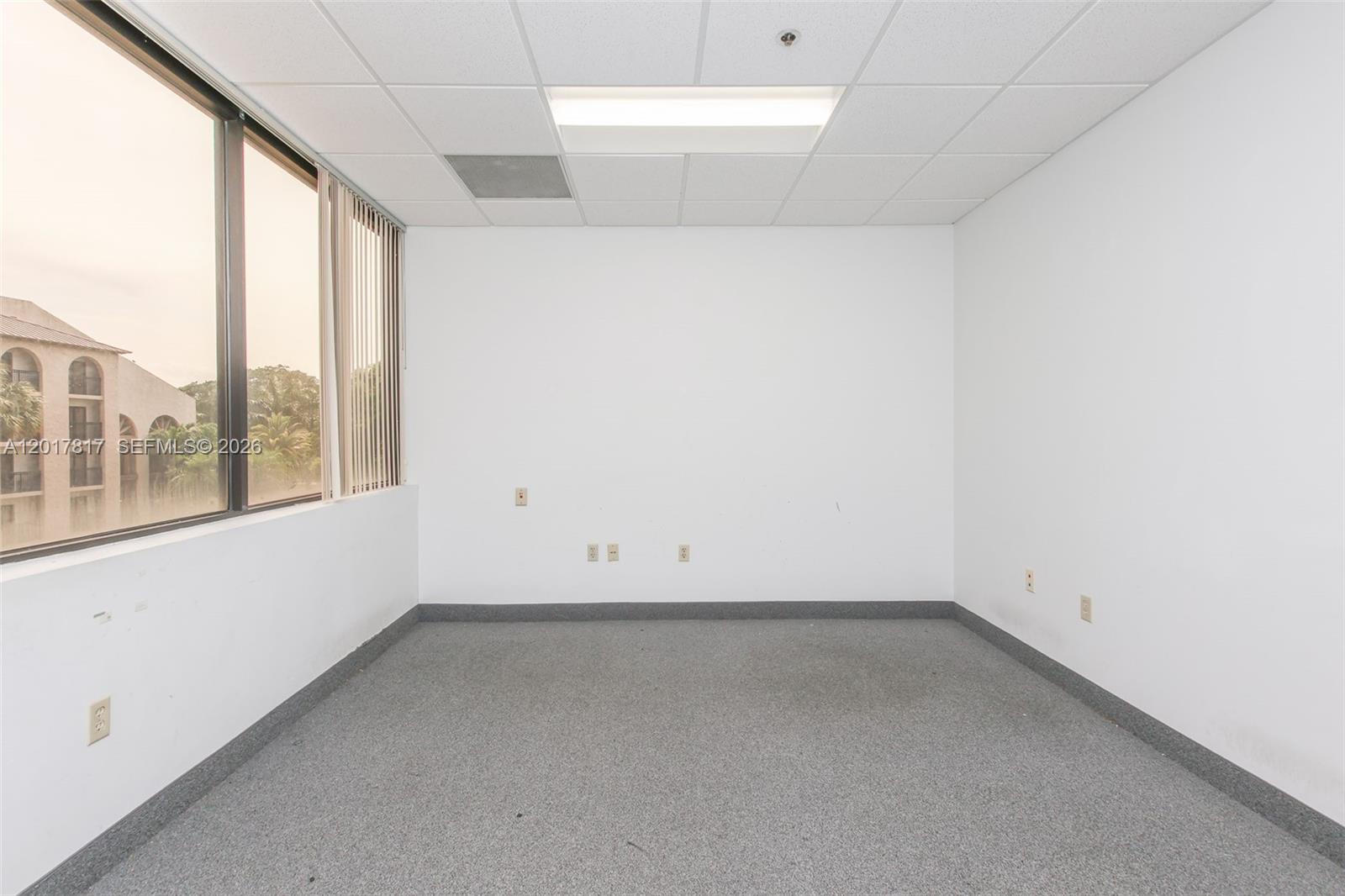 An empty office space features white walls, gray carpeting, a drop ceiling, and large windows — 1900 Glades Rd # 280, Boca Raton FL 33431, BOCA RATON, FL