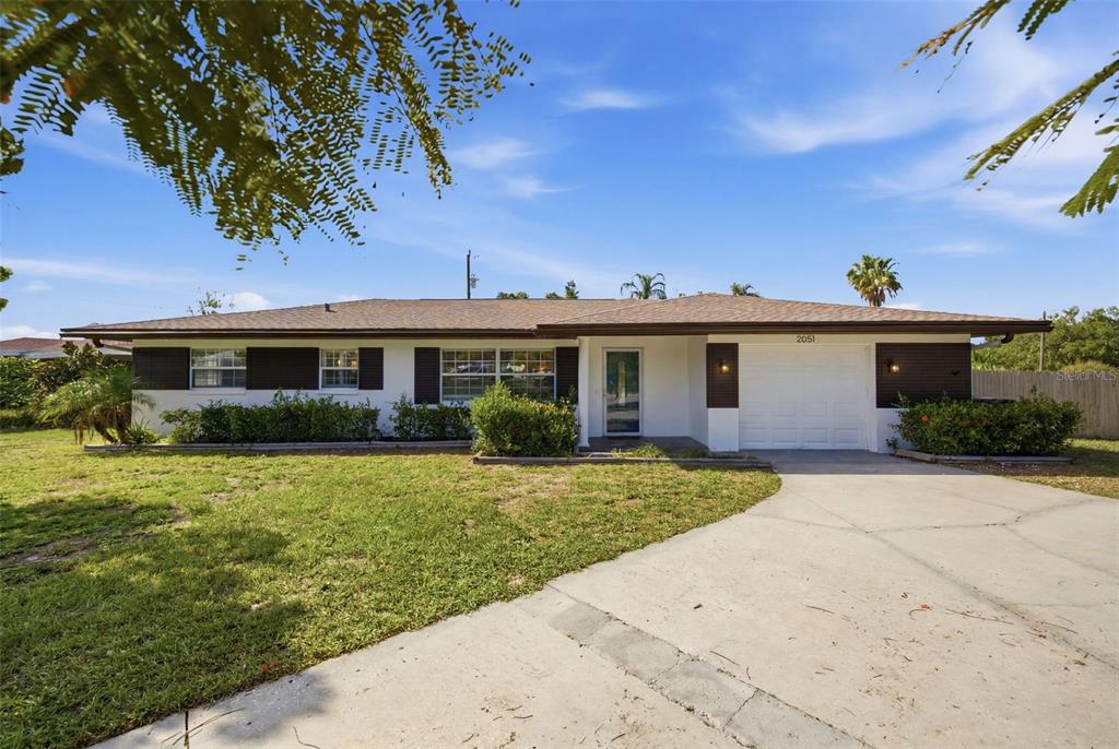 A single-story house with a white exterior, dark shutters, and a concrete driveway — 2051 MAGNOLIA DRIVE, CLEARWATER, FL