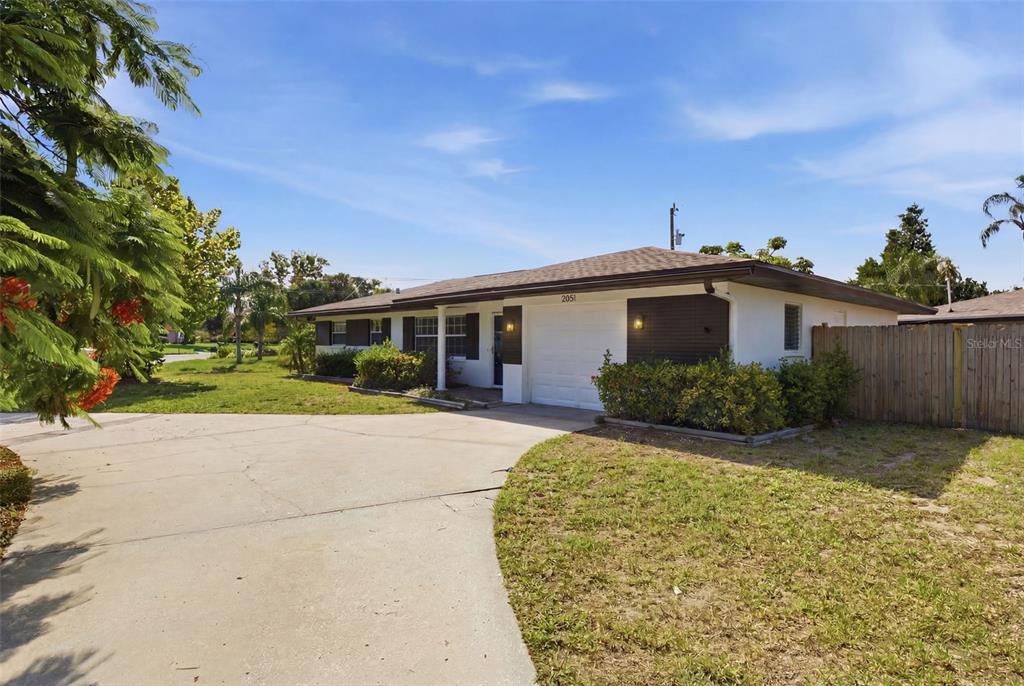 A single-story house with a white exterior, dark wood accents, and a concrete driveway — 2051 MAGNOLIA DRIVE, CLEARWATER, FL