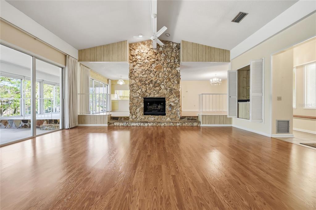 A living room features hardwood floors, a stone fireplace, and a vaulted ceiling with fans — 1352 ERROL PARKWAY, APOPKA, FL