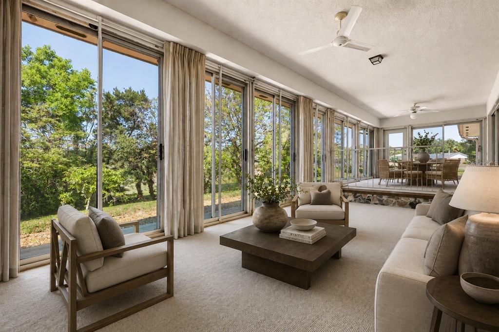 A sunroom features floor-to-ceiling windows, neutral furniture, a coffee table, and an elevated dining area — 1352 ERROL PARKWAY, APOPKA, FL