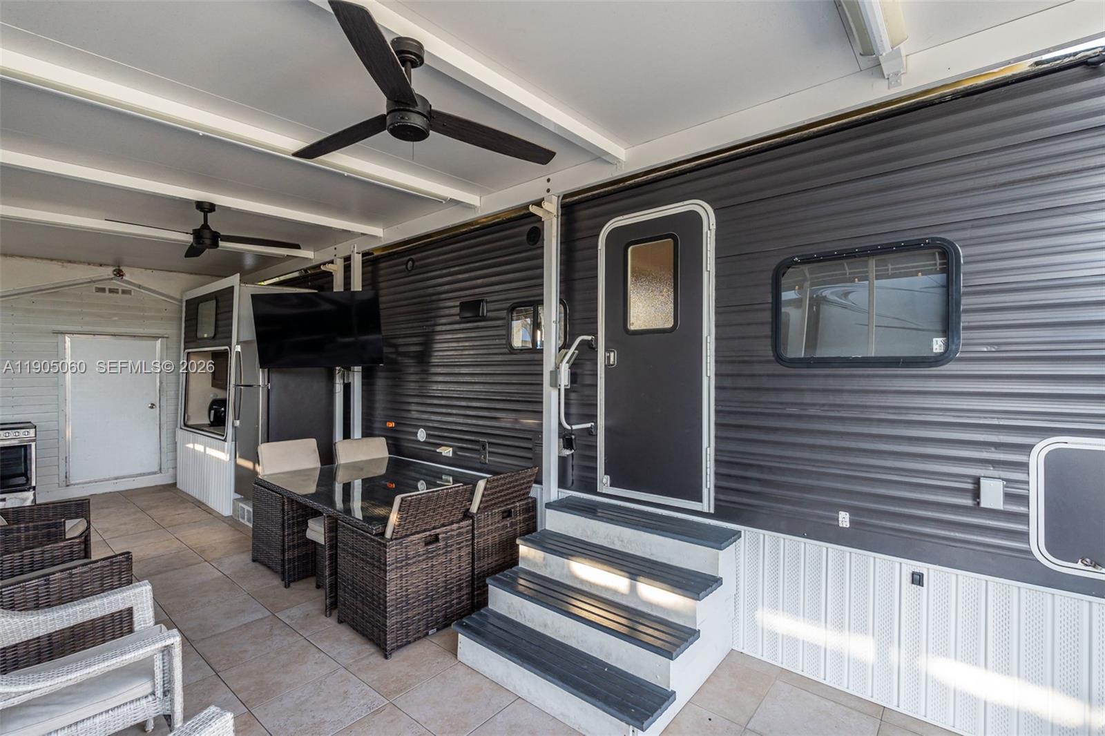 An outdoor patio features a dining set, a television, and steps leading to a trailer — 325 Calusa St 44, Key Largo FL 33037, KEY LARGO, FL