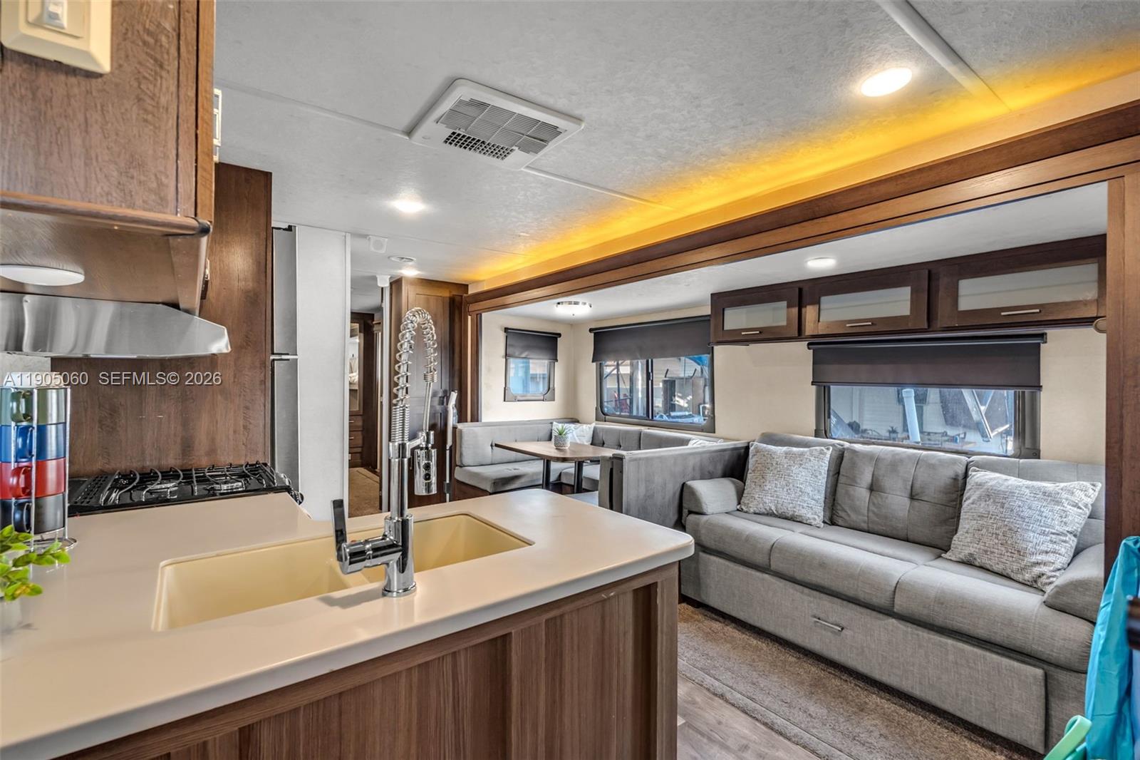 A kitchen island with a sink faces a living area with a sofa and booth seating — 325 Calusa St 44, Key Largo FL 33037, KEY LARGO, FL
