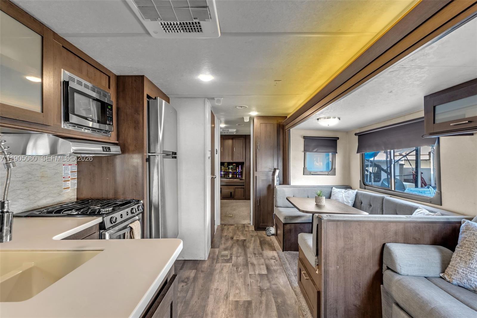 A kitchen and dining area in an RV featuring wood cabinets, stainless appliances, and seating — 325 Calusa St 44, Key Largo FL 33037, KEY LARGO, FL
