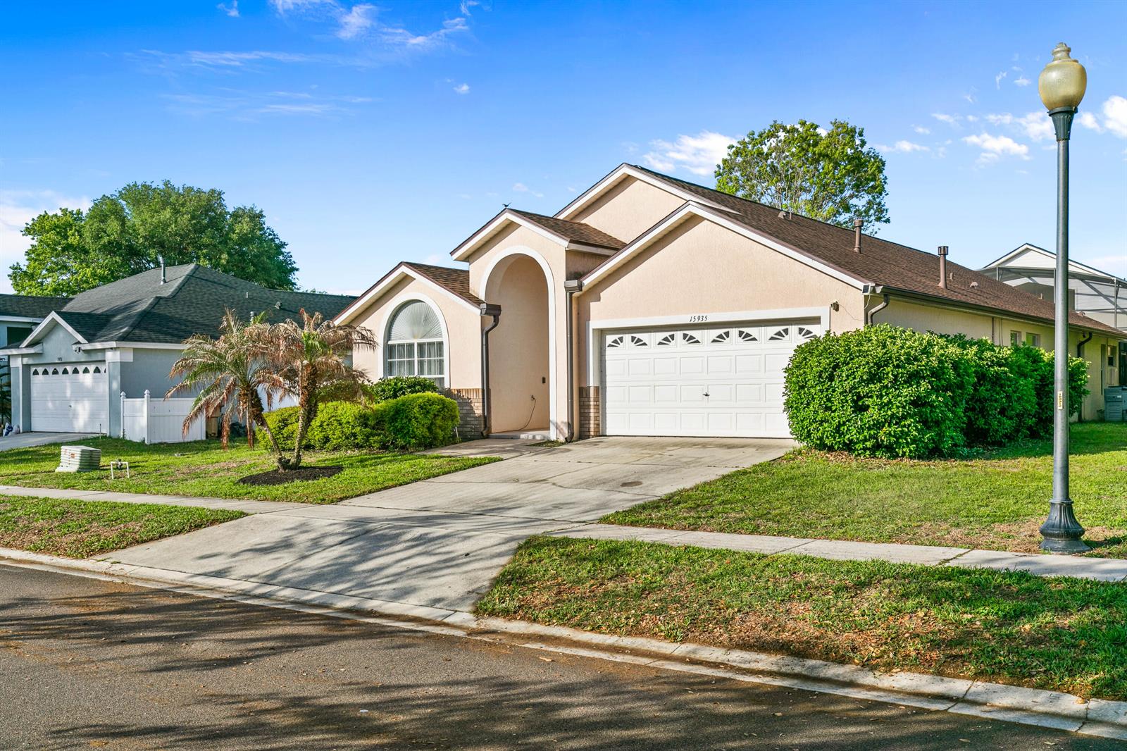 A single-story suburban house with a beige stucco exterior, a two-car garage, and a driveway — 15935 Heron Hill Street, Clermont FL 34714, CLERMONT, FL