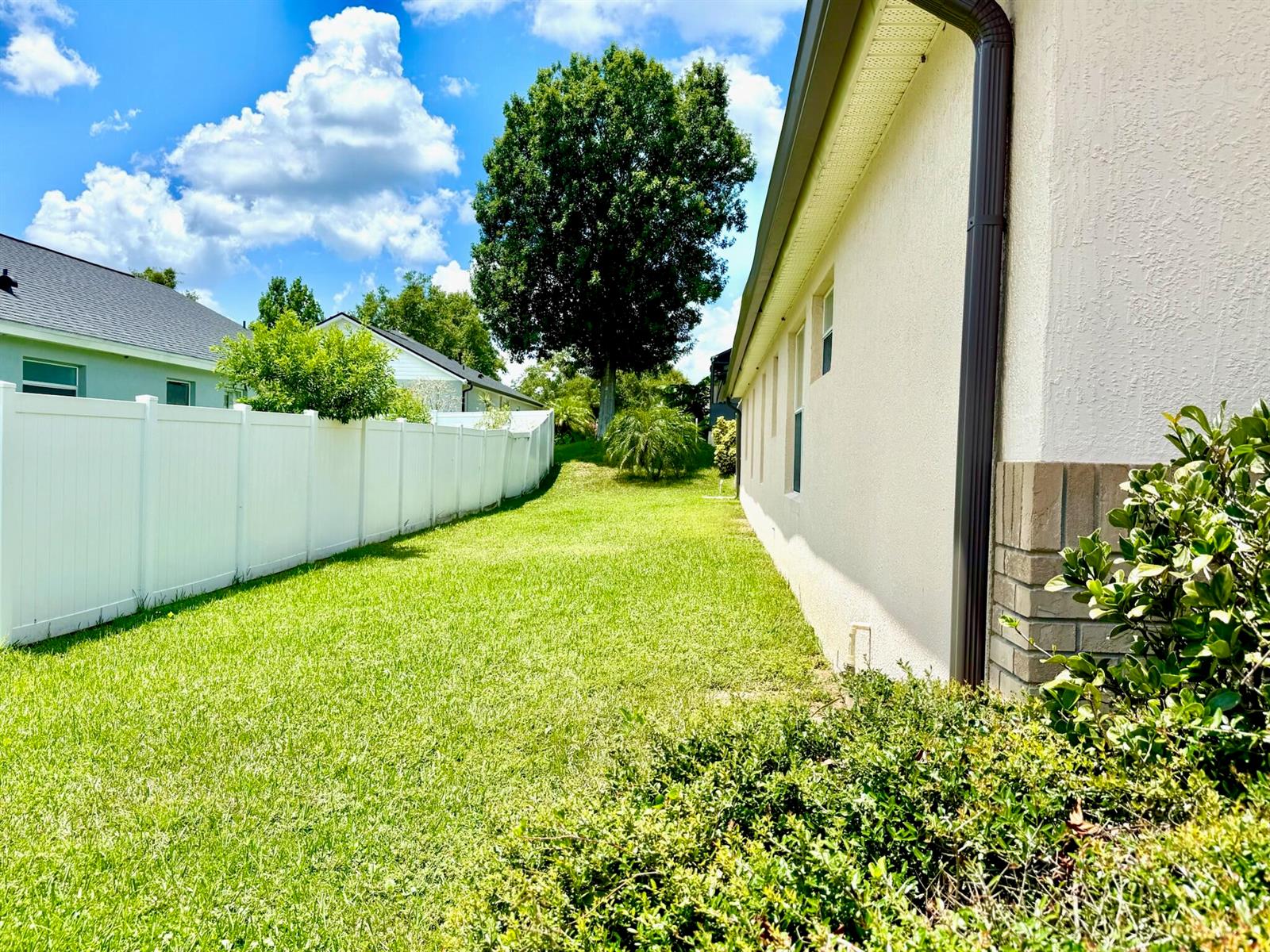 A side yard features a green lawn, a white vinyl fence, and a beige house — 15935 Heron Hill Street, Clermont FL 34714, CLERMONT, FL