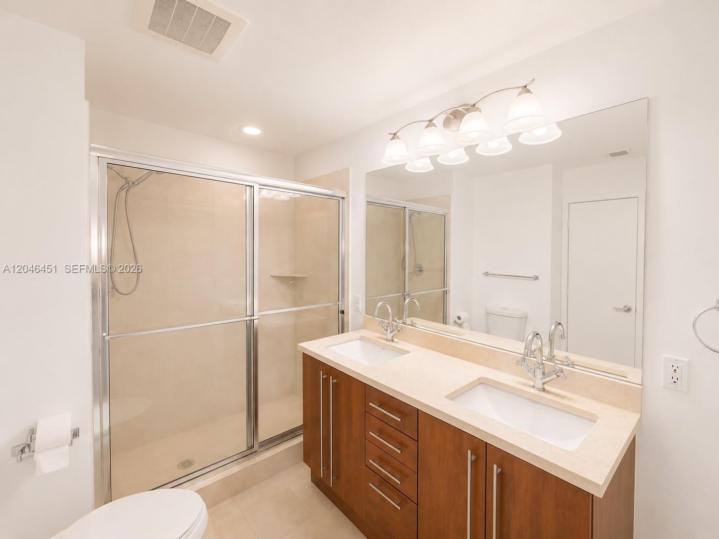 A bathroom features a double vanity with a light countertop, wood cabinets, and a shower — 1111 SW 1st Ave, Miami FL 33130, MIAMI, FL