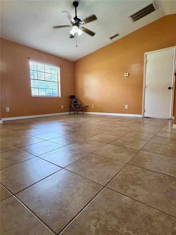 An empty room features tan walls, a vaulted ceiling with a fan, and tiled flooring — 348 CORNWALLIS COURT, KISSIMMEE, FL