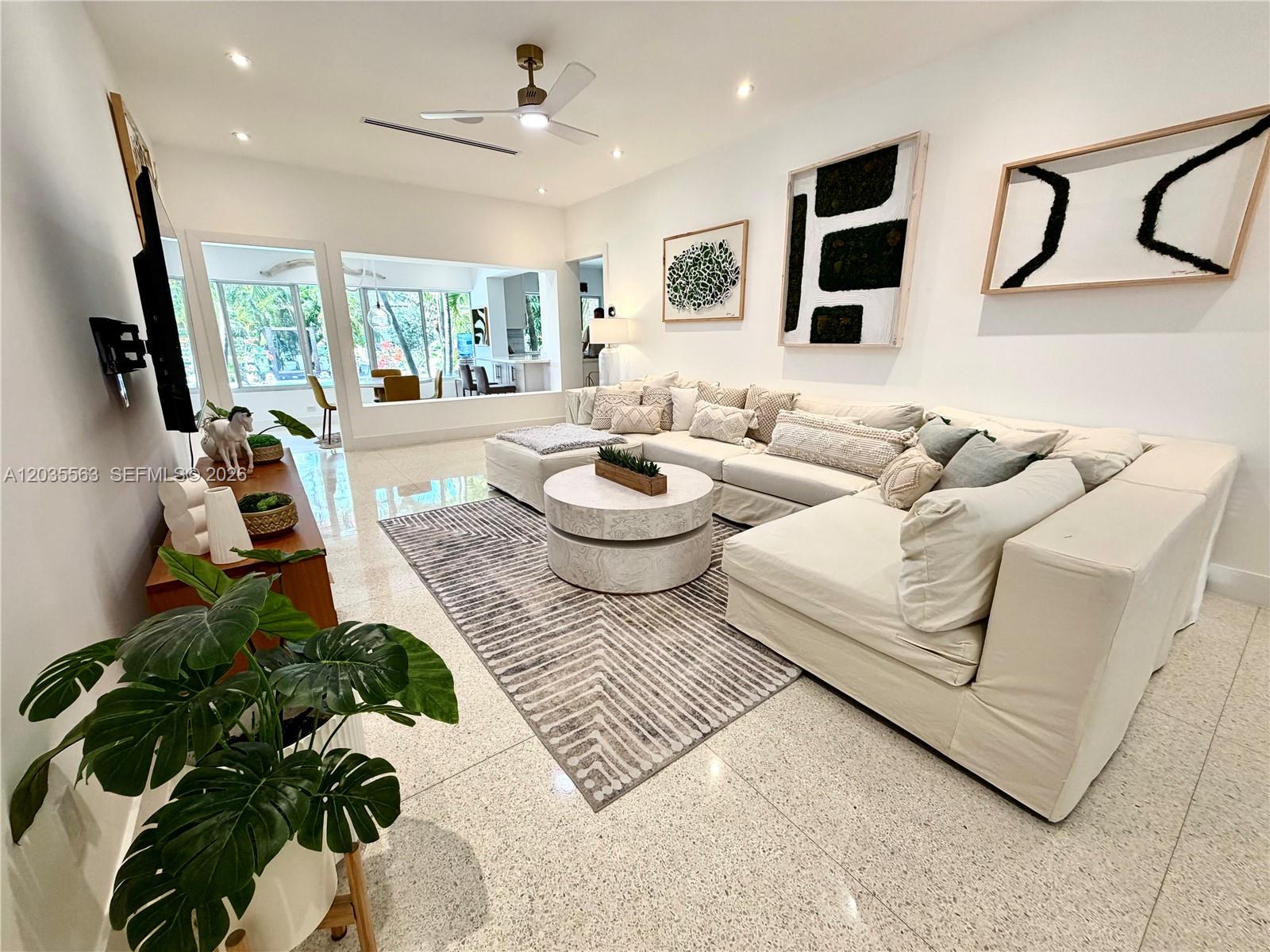 A bright living room features a large sectional sofa, patterned rug, and modern wall art — 1460 Cleveland Rd, Miami Beach FL 33141, MIAMI BEACH, FL