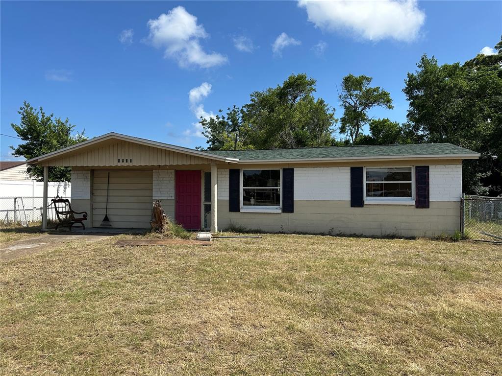 A single-story house with a beige brick exterior, a green roof, and a red door — 4923 STATE ROAD 54, NEW PORT RICHEY, FL
