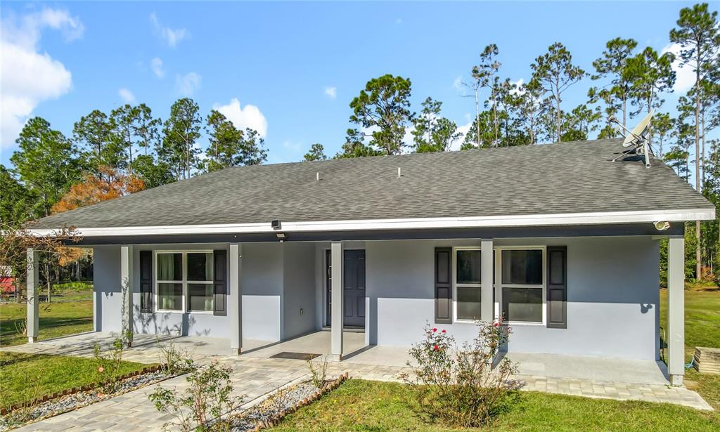 A single-story house with a gray exterior, a covered front porch, and a paved walkway — 6100 WINNING WOOD TRAIL, DE LEON SPRINGS, FL