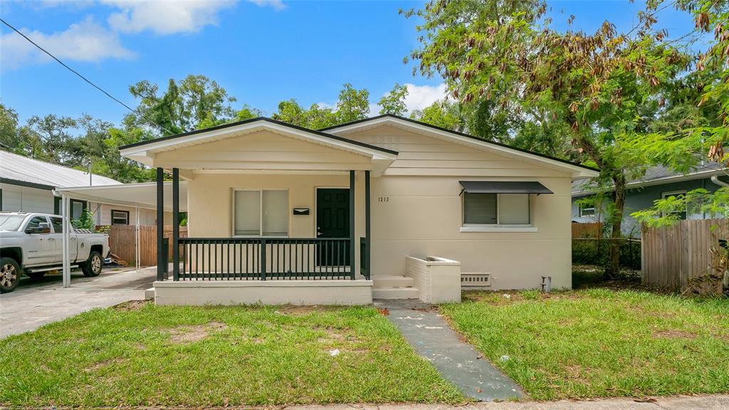 A single-story house with a covered front porch, a black door, and a concrete driveway — 1213 E 24TH AVENUE, TAMPA, FL