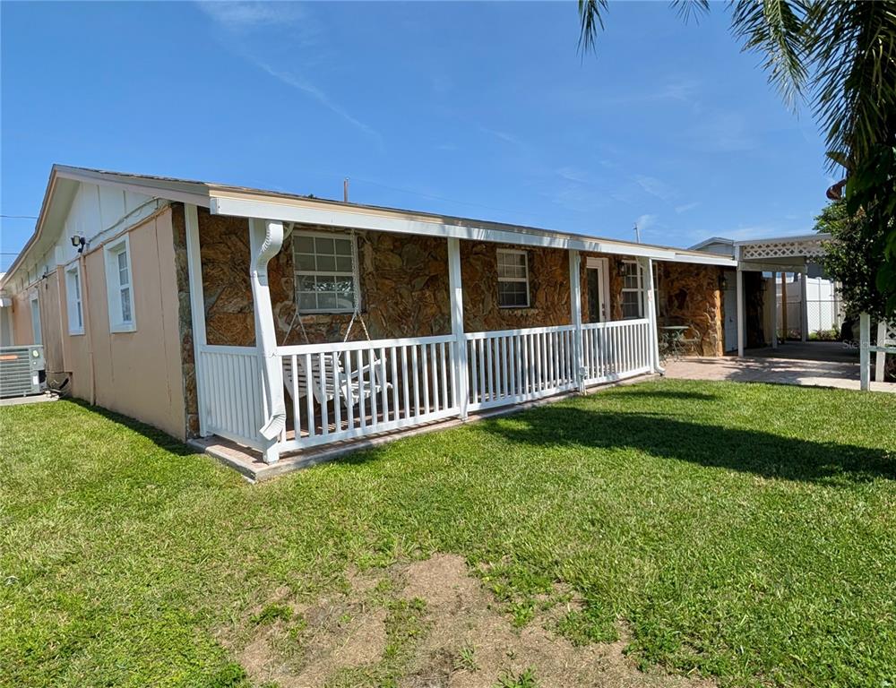 A single-story house with a stone facade, a white porch railing, and a side carport — 6006 N HUBERT AVE, TAMPA, FL
