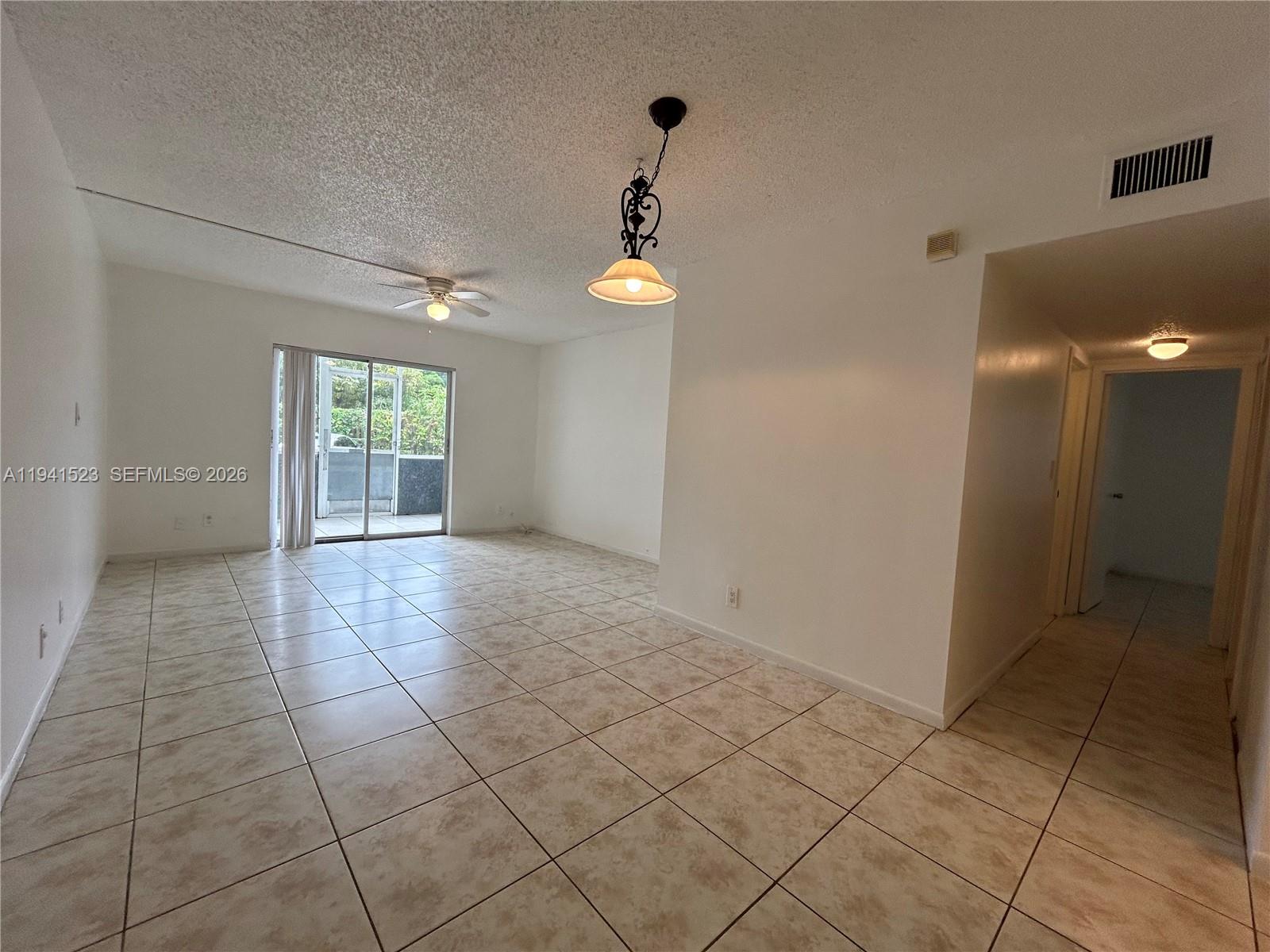 An open living area features beige tile flooring, a ceiling fan, and a sliding glass door — 4354 NW 9th Ave # 1C, Deerfield Beach FL 33064, DEERFIELD BEACH, FL