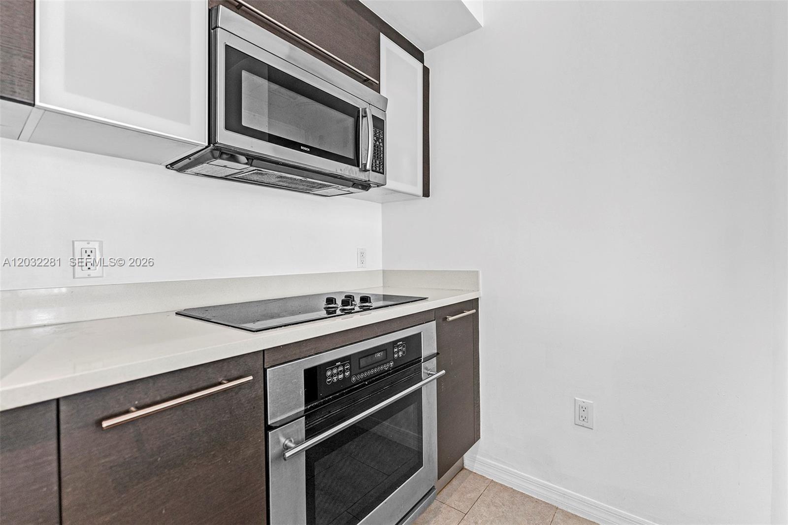 A kitchen features dark wood cabinets, stainless steel appliances, and a light-colored countertop — 55 SE 6th St # 1208, Miami FL 33131, MIAMI, FL