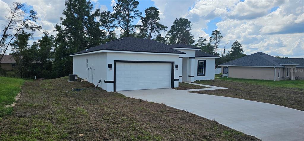 A white single-story house with a black roof and a two-car garage — 2648 SW 146 TH PLACE ROAD, OCALA, FL