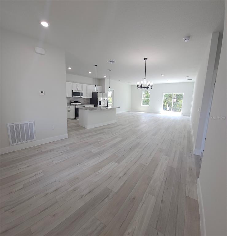 An open-concept kitchen and living area features white cabinetry, a center island, and light-colored flooring — 2648 SW 146 TH PLACE ROAD, OCALA, FL