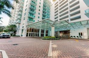 The exterior of a high-rise residential building features a glass porte-cochère and brick driveway — 31 SE 5th St # 705, Miami FL 33131, MIAMI, FL