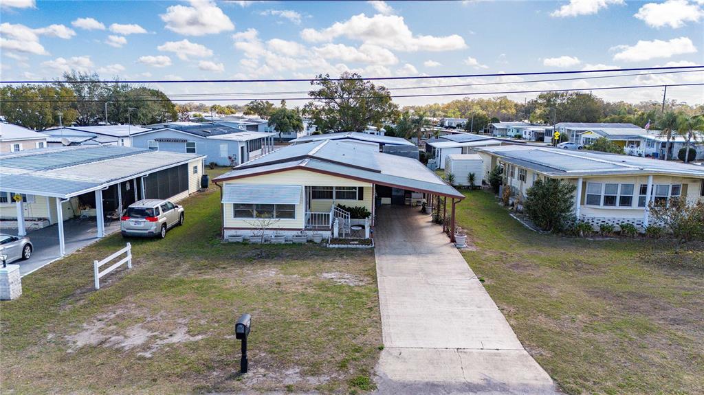 An aerial view shows a yellow mobile home with a carport and a concrete driveway — 5250 DEAN DAIRY ROAD, ZEPHYRHILLS, FL