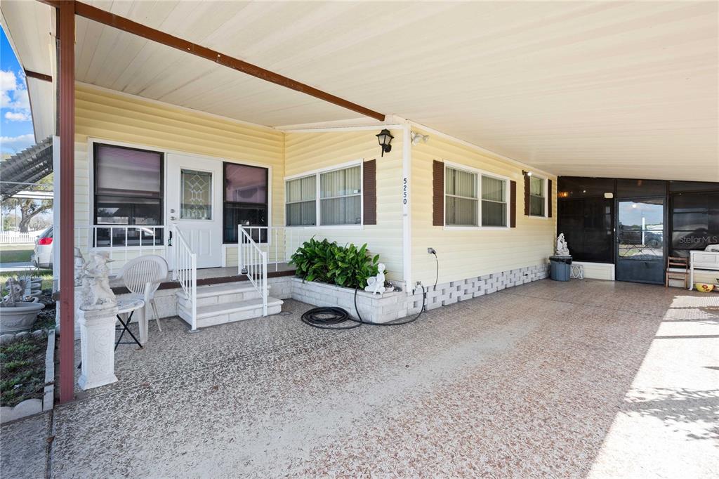 A yellow mobile home features a covered carport, a front porch, and concrete flooring — 5250 DEAN DAIRY ROAD, ZEPHYRHILLS, FL