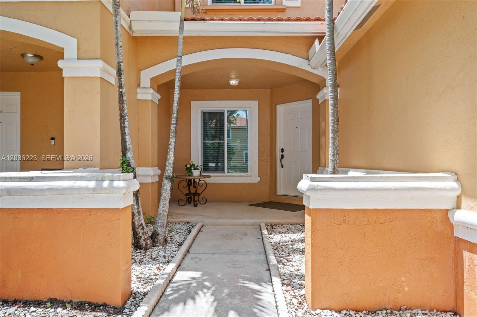 A concrete walkway leads to the covered entryway of a stucco home with palm trees — 6086 Southard St, West Palm Beach FL 33411, WEST PALM BEACH, FL