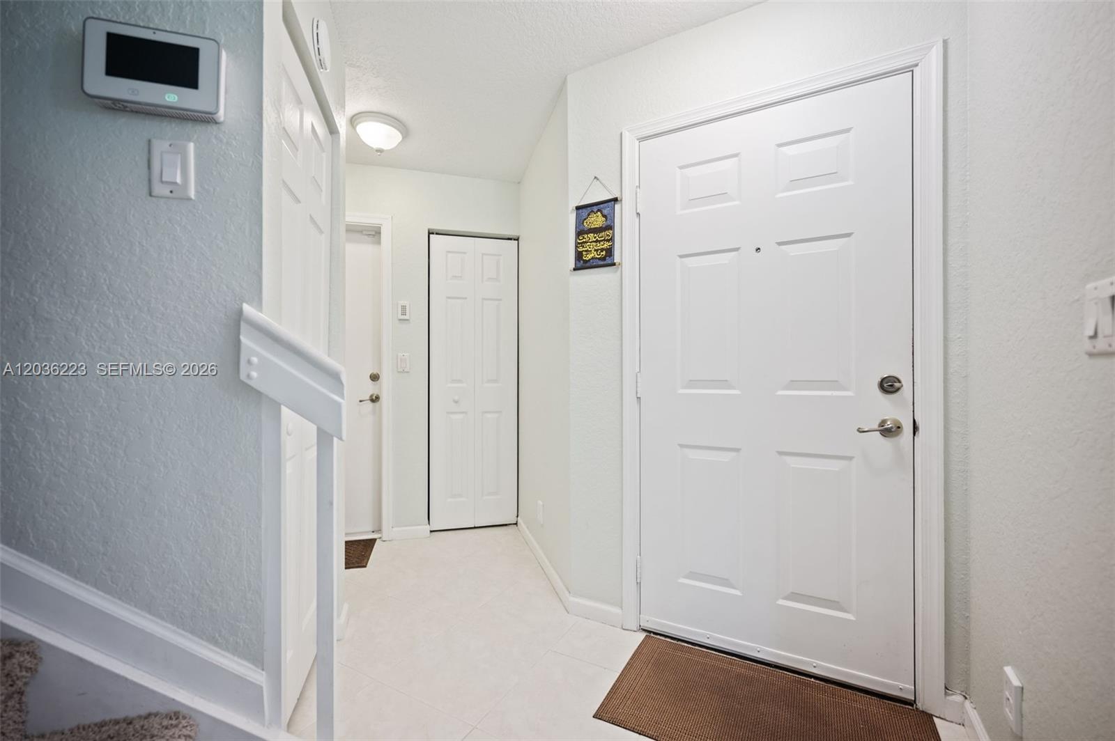 An entryway features a white front door, tiled flooring, and a staircase with white railings — 6086 Southard St, West Palm Beach FL 33411, WEST PALM BEACH, FL