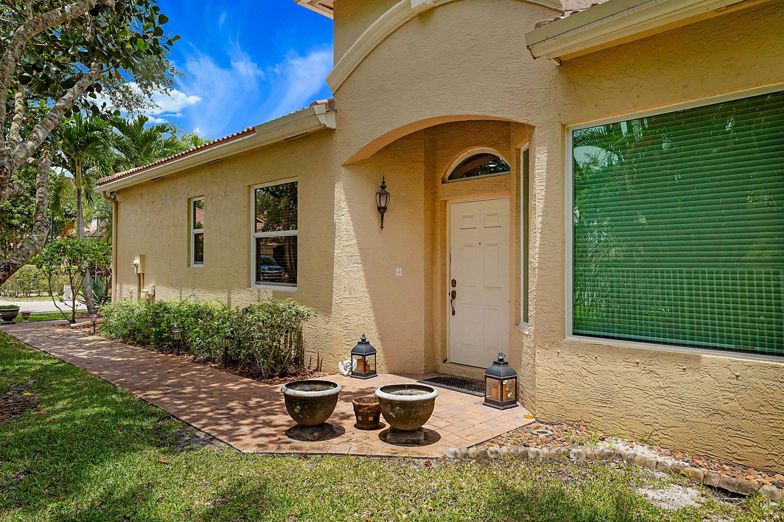 The exterior of a beige stucco house features a front door, walkway, and landscaping — 2568 Sandy Cay, West Palm Beach FL 33411, WEST PALM BEACH, FL