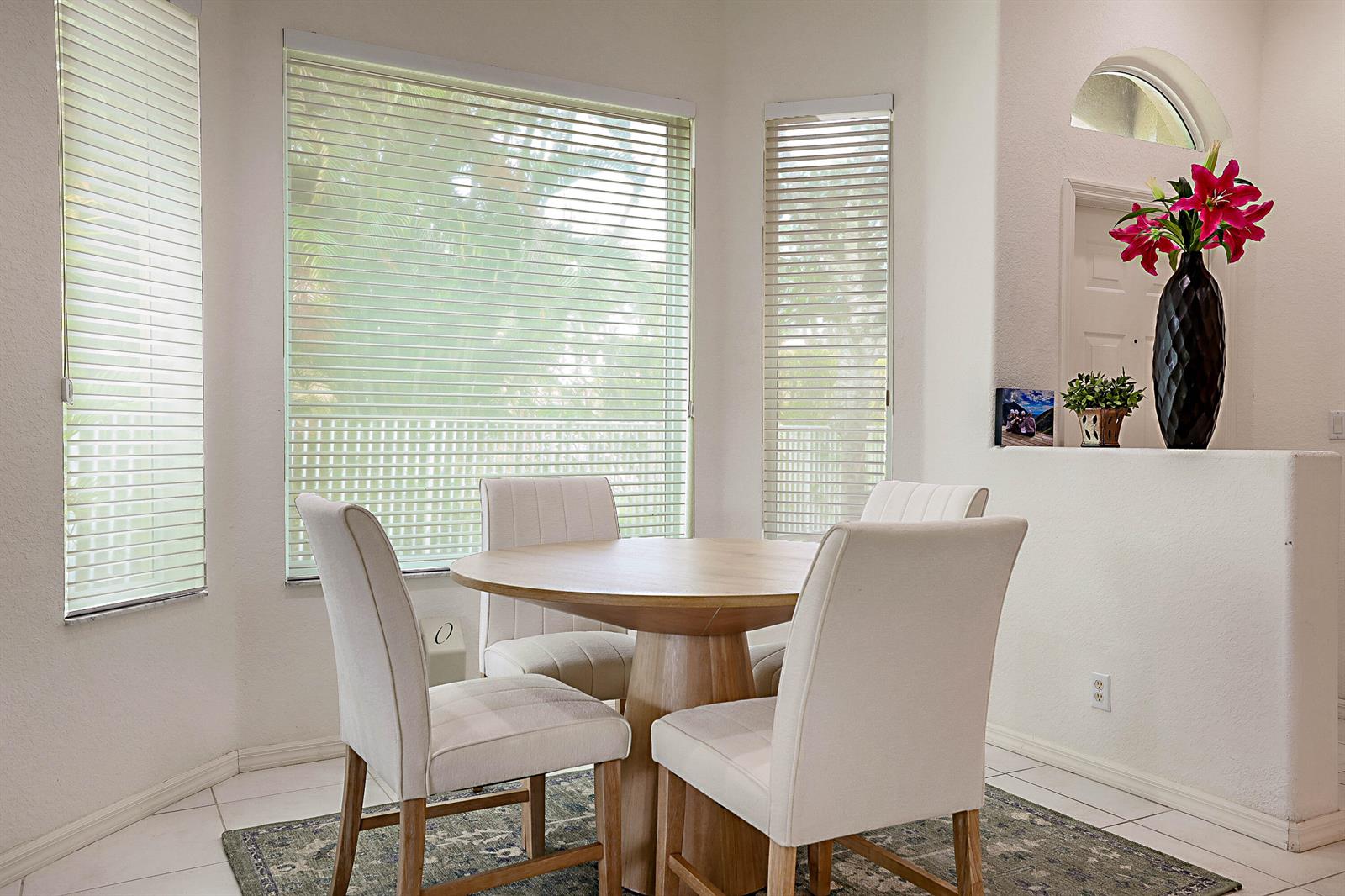 A dining area features a round wooden table, four upholstered chairs, and large windows with blinds — 2568 Sandy Cay, West Palm Beach FL 33411, WEST PALM BEACH, FL