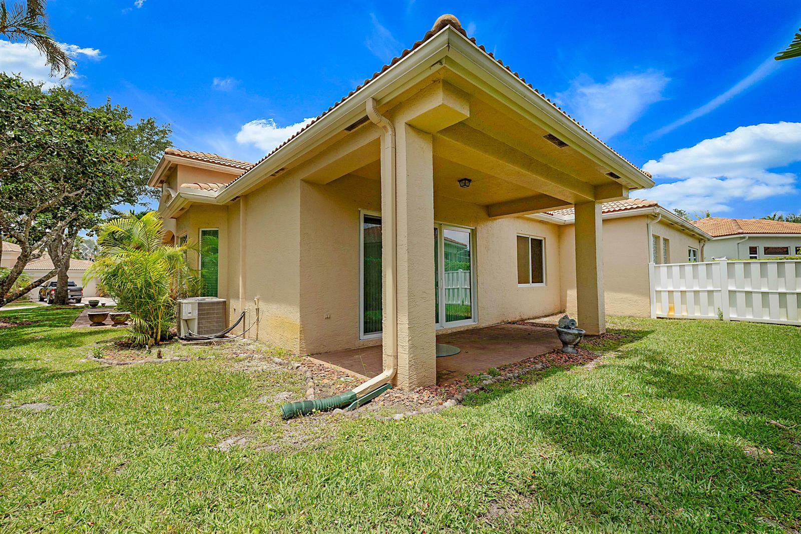 A beige stucco house features a covered patio, a tiled roof, and a grassy yard — 2568 Sandy Cay, West Palm Beach FL 33411, WEST PALM BEACH, FL