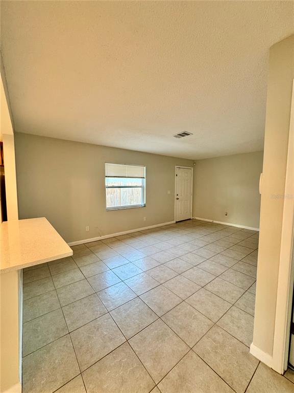 An empty room features light-colored tile flooring, beige walls, a window, and a white door — 2564 42ND AVENUE N, ST PETERSBURG, FL