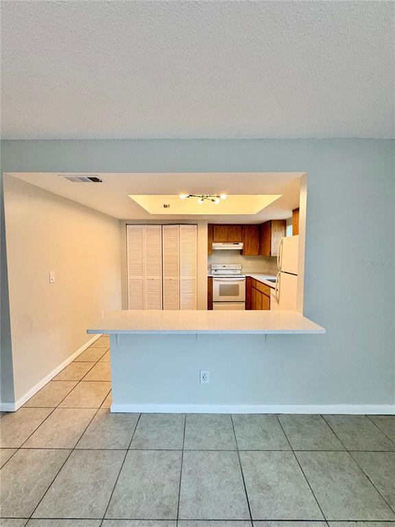 A kitchen with wood cabinets and white appliances is viewed across a breakfast bar — 2564 42ND AVENUE N, ST PETERSBURG, FL