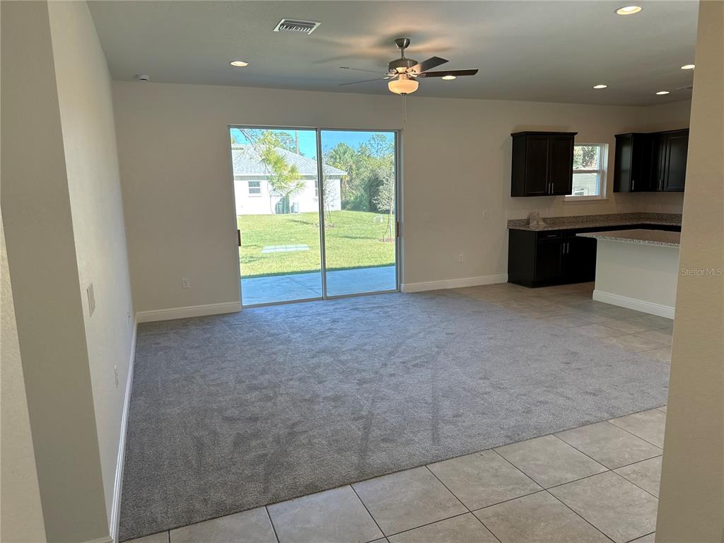 A living room with gray carpet features a sliding glass door leading to a backyard — 1464 SHADOW LANE, NORTH PORT, FL