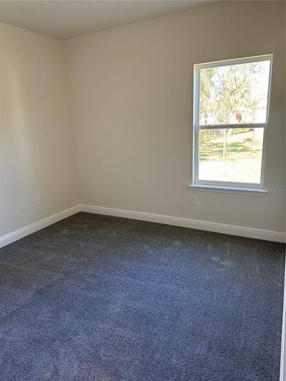 An empty bedroom features gray carpeting, light-colored walls, and a single window — 1464 SHADOW LANE, NORTH PORT, FL