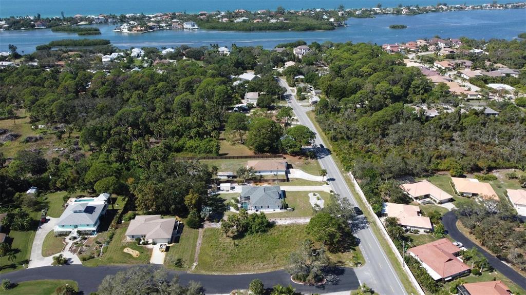 An aerial view shows a residential neighborhood with houses, dense trees, and a nearby waterway — 0 LAUREL WOODS DRIVE, NOKOMIS, FL
