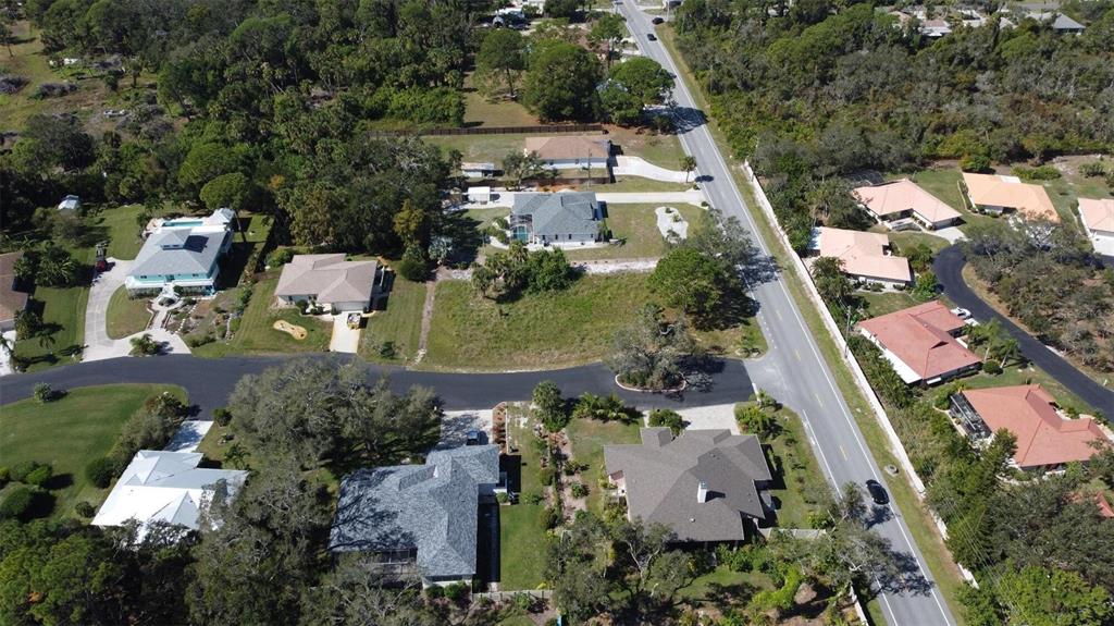 An aerial view shows several suburban houses surrounded by trees and a paved road — 0 LAUREL WOODS DRIVE, NOKOMIS, FL