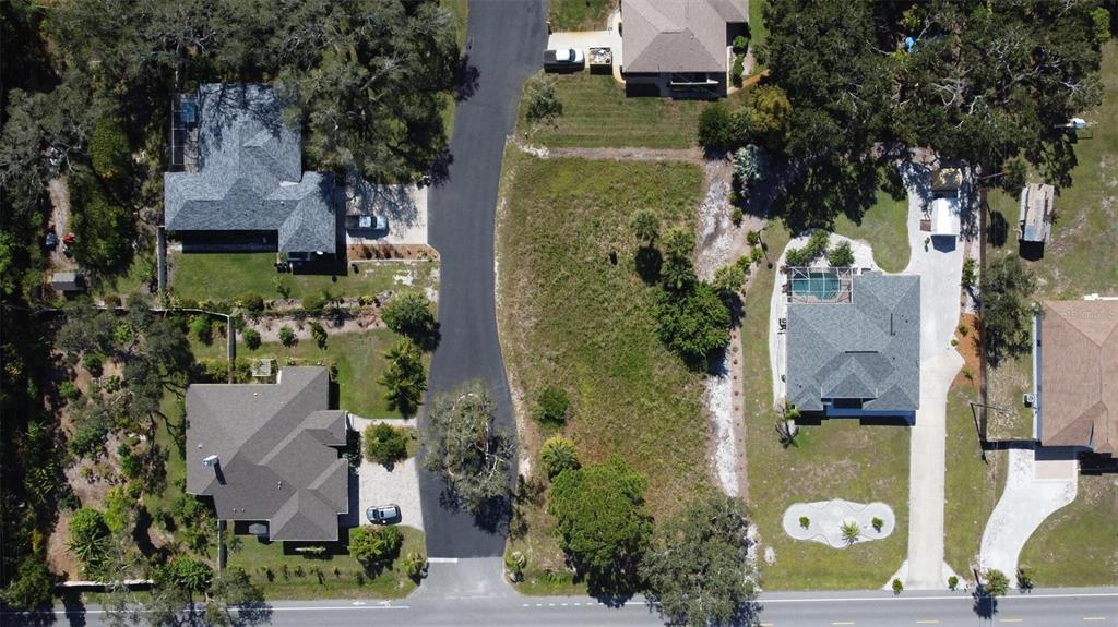 An aerial view shows a vacant grassy lot situated between two houses on a paved street — 0 LAUREL WOODS DRIVE, NOKOMIS, FL