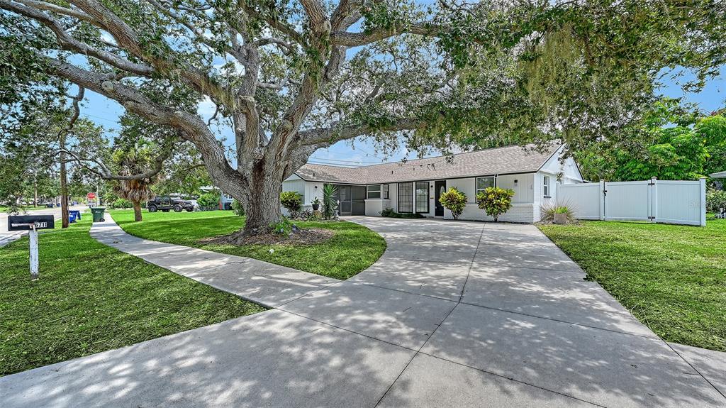 A single-story white house with a large oak tree and a concrete driveway — 6711 S LOCKWOOD RIDGE ROAD, SARASOTA, FL