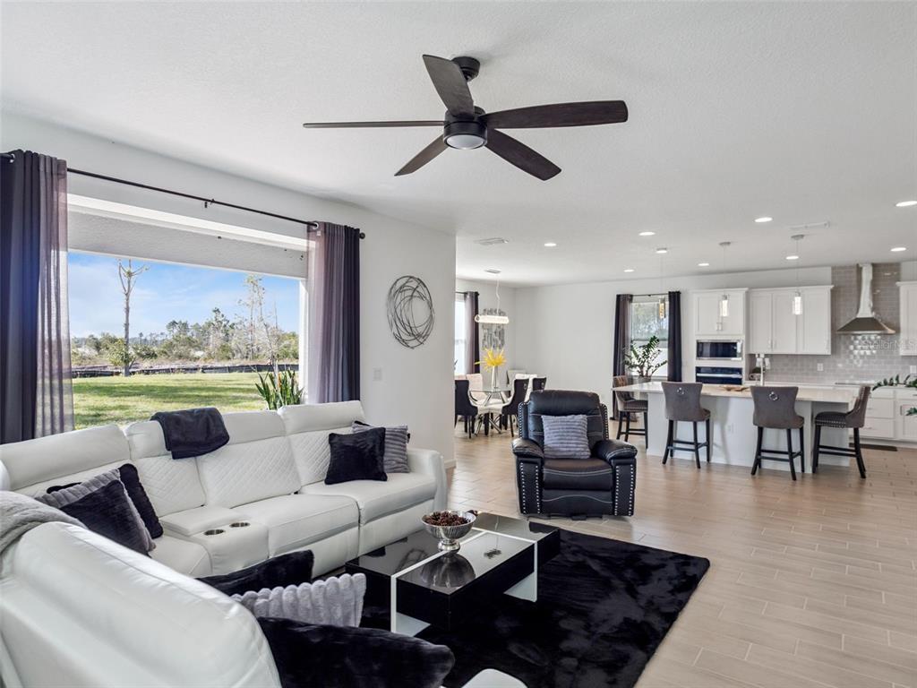A modern open-concept living room and kitchen featuring white furniture, a black rug, and tile — 591 VIA BELLA COURT, HOWEY IN THE HILLS, FL